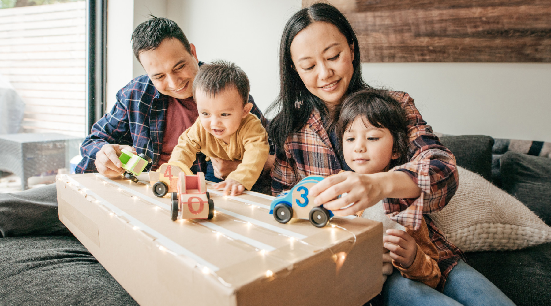 Young family playing with wooden toy cars