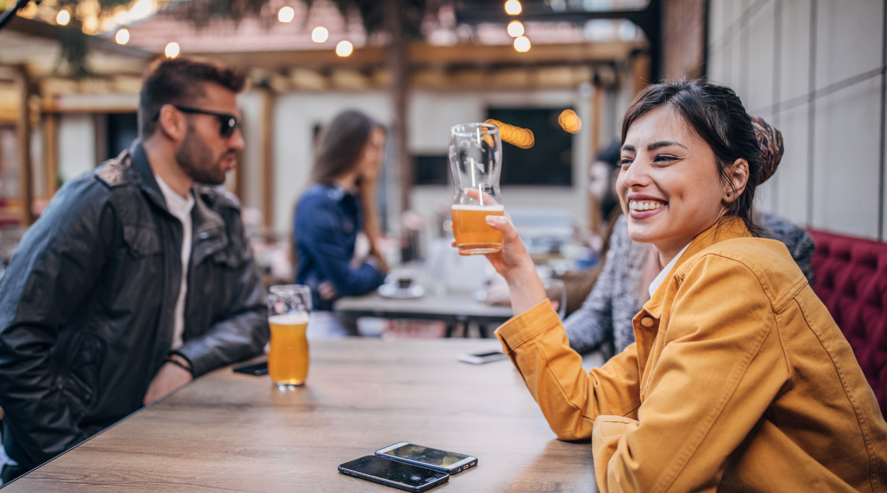 Woman smiling and enjoying a beer at a restaurant