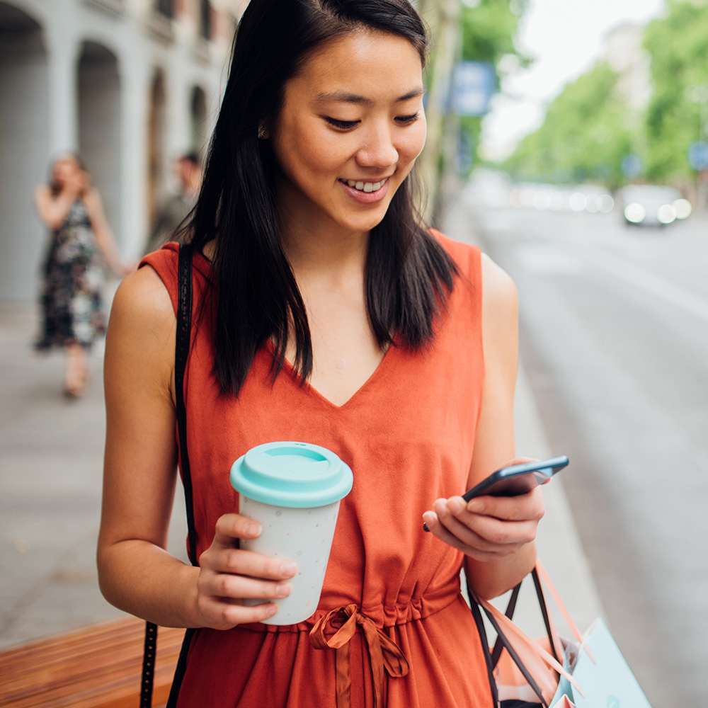 Happy woman with coffee and cell phone